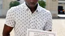 Imigran asal Mali, Mamoudou Gassama menunjukkan sertifikat penghargaan di Paris, Prancis, Senin (29/5). Gassama mendapat penghargaan setelah memanjat gedung apartemen untuk menyelamatkan balita yang hampir jatuh. (AP Photo/Thibault Camus, Pool)