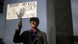 Seorang warga membawa poster saat long march di jalanan Meksiko City, Meksiko, Selasa (26/4). 19 bulan berlalu, keluarga korban mendesak pemerintah menginvestigasi lebih lanjut terkait kasus hilangnya 43 mahasiswa tersebut. (REUTERS/Edgard Garrido)