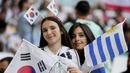Suporter wanita Korea Selatan juga berbaur dengan suporter Uruguay. Itu terlihat saat keduanya berpose bersama sebelum laga dimulai. (AP Photo/Martin Meissner)
