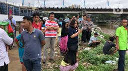 Warga bersama personel kepolisian berkumpul di bantaran Sungai Ciliwung, Jakarta, Selasa (25/2/2020). Adanya seorang warga yang hanyut saat berenang di tengah luapan Sungai Ciliwung tersebut mengundang perhatian warga serta petugas yang mencari keberadannya. (Liputan6.com/Immanuel Antonius)