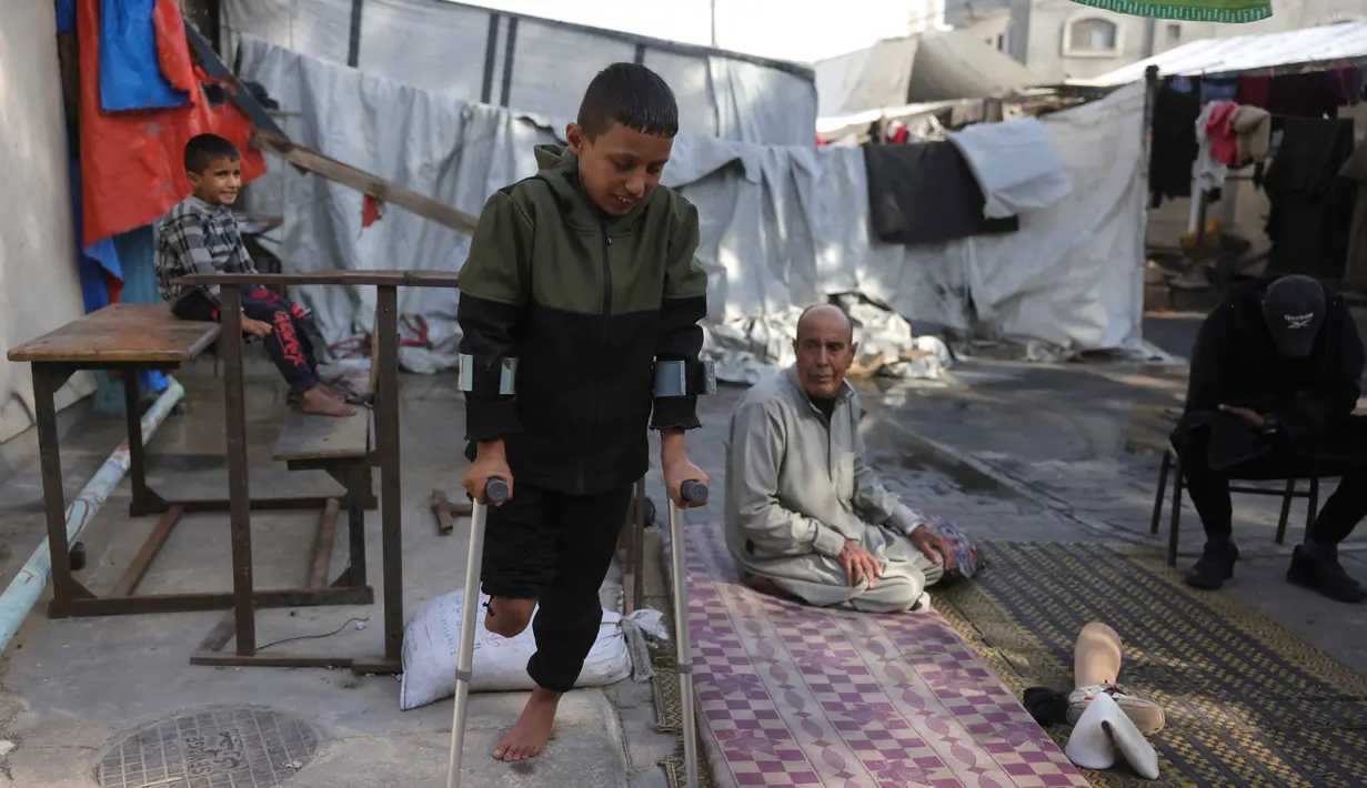 Saat ini, Rateb Mahmoud Qaliq, yang berasal dari desa Badui di Jalur Gaza utara, mengungsi dan tinggal bersama kakeknya di sebuah sekolah UNRWA di Deir al-Balah, Jalur Gaza tengah, yang berfungsi sebagai tempat penampungan. Tampak dalam foto, Rateb Mahmoud Qaliq bersama kakeknya di halaman sekolah UNRWA yang telah menjadi tempat penampungan bagi pengungsi Palestina di Deir al-Balah, di Jalur Gaza tengah, pada 3 Desember 2025. (Bashar Taleb/AFP)