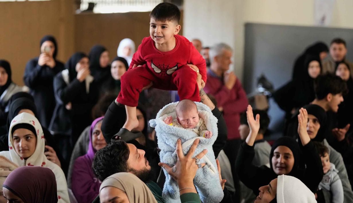 Sebagai informasi, hingga Maret 2026, eskalasi serangan udara Israel di Beirut, Lebanon, semakin intensif. Tampak dalam foto, para pria mengangkat dua anak kecil selama acara di mana para sukarelawan menyiapkan bingkisan makanan dan manisan Idulfitri untuk keluarga pengungsi yang merayakan hari raya jauh dari rumah mereka, di sebuah universitas negeri yang diubah menjadi tempat penampungan setelah serangan udara Israel di Beirut, Lebanon, Jumat, 20 Maret 2026. (AP Photo/Hassan Ammar)