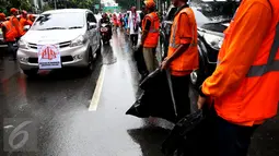 Kendaraan peserta aksi damai 2 Desember melewati pasukan oranye (petugas kebersihan) yang disiagakan di kawasan Monas, Jakarta, Jumat (2/12). Pasukan oranye dibekali kantong plastik besar untuk memungut sampah yang berserakan. (Liputan6.com/Johan Tallo)