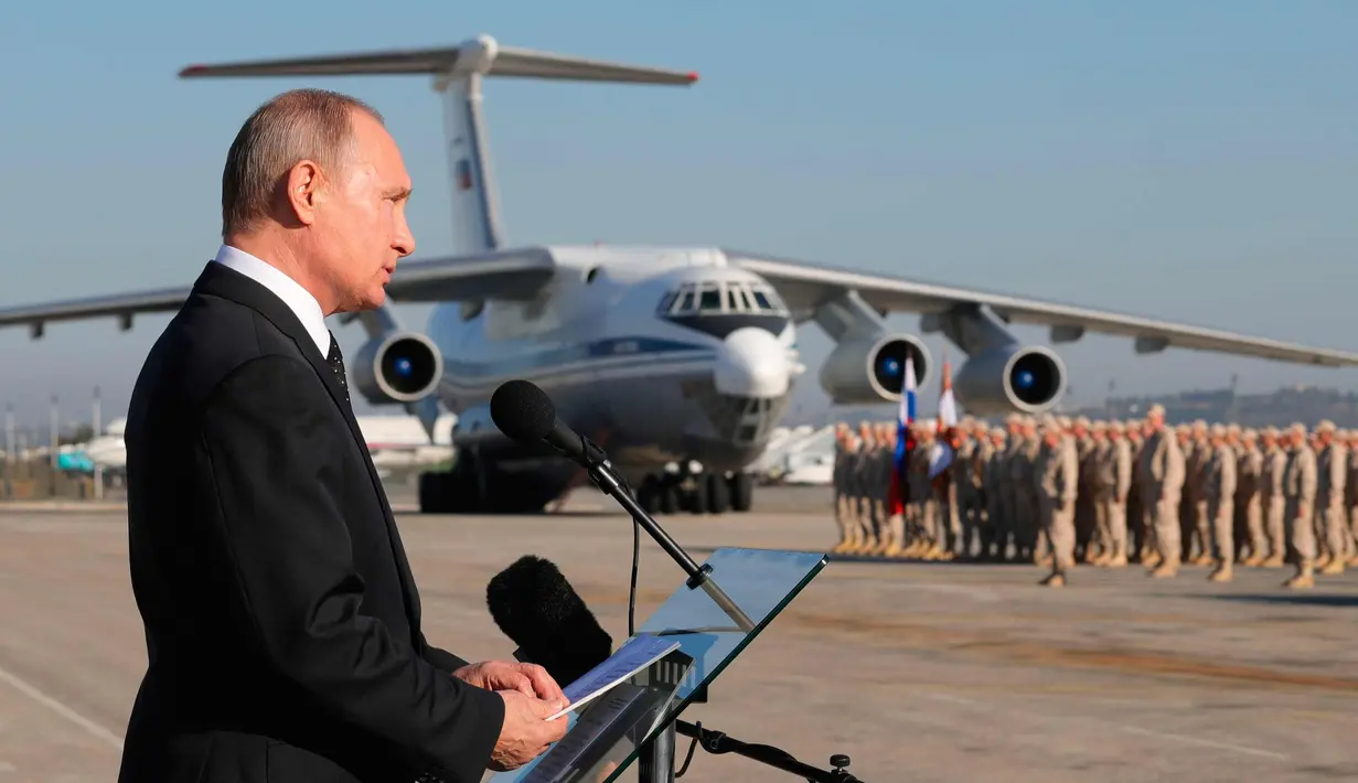 Presiden Rusia, Vladimir Putin memberi sambutan saat tiba di pangkalan udara Hemeimeem di Suriah (11/12). Kunjungan Putin sebagai bentuk dari perayaan di Suriah. (Mikhail Klimentyev, Sputnik, Kremlin Pool Photo via AP)
