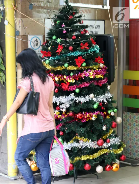 Warga melintas di dekat pohon Natal di Terowongan Penyebrangan Orang (TPO) Kota Tua, Jakarta, Jumat (21/12). Jelang perayaan Natal 2018, TPO Kota Tua dihiasi pernak-pernik. (Liputan6.com/Helmi Fithriansyah)