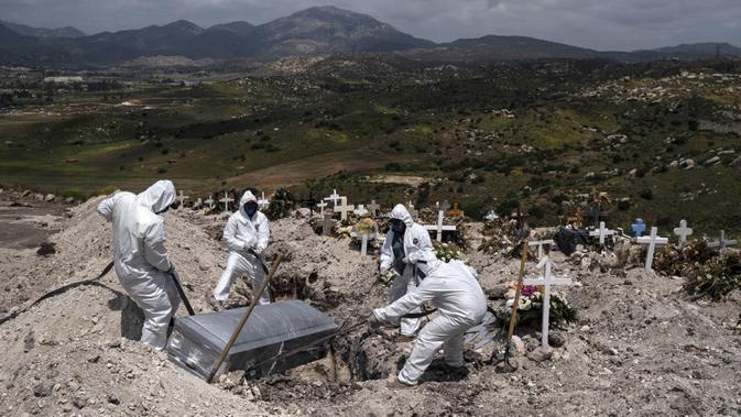 Pekerja mengenakan alat pelindung diri saat mengubur korban meninggal akibat virus corona COVID-19 di pabrik semen No. 13 di Tijuana, Baja California, Meksiko, 21 April 2020. (Photo by Guillermo Arias/AFP)