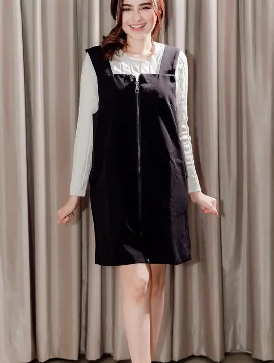 Syifa Hadju tampil menggemaskan dengan mini dress overall warna hitam dipadukan inner celana putih knit lengan panjang. Serta mengenakan boots heels hitam. [@syifahadju]