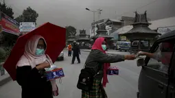 Relawan membagikan masker kepada pengendara kendaraan di kawasan Berastagi, Karo, Sumatera Utara, 25 Juni 2015. Debu vulkanik akibat erupsi Gunung Sinabung masih menutupi sebagian Kota Berastagi. (REUTERS/Beawiharta)