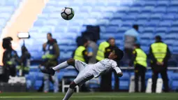 Putra dari Cristiano Ronaldo bersiap melakukan tendangan salto saat menemani sang ayah di Stadion Santiago Bernabeu, Madrid, Minggu (8/4/2018). Tendangan ini mirip seperti saat CR 7 membobol gawang Juventus. (AFP/Gabriel Bouys).