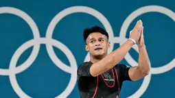 Rizki Juniansyah berhasil mencatat total angkatan 354 kg usai sukses mengangkat beban 155 kg snatch dan 199 kg clean and jerk. (Miguel MEDINA/AFP)