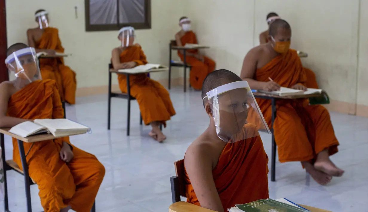 Para biksu muda mengenakan masker dan pelindung wajah saat belajar agama di Molilokayaram Educational Institute, Bangkok, Thailand, Rabu (15/4/2020). Sekitar 200 biksu muda tetap bersekolah kendati Thailand menutup semua sekolah selama lockdown akibat COVID-19. (AP Photo/Gemunu Amarasinghe)