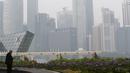 Seorang pria saat berada disamping skyline yang dikelilingi kabut tebal di Singapura (25/9/2015). Sejak Rabu Kualitas udara di Singapura mulai memburuk akibat kabut asap tebal dari wilayah Indonesia. (REUTERS/Edgar Su)