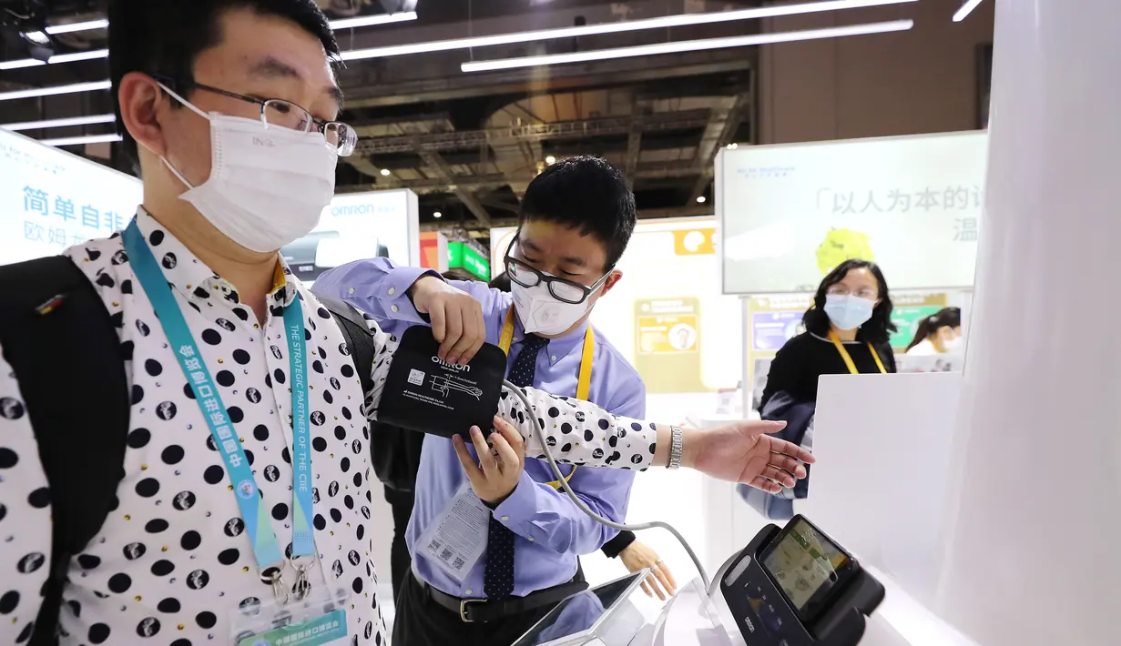Seorang pengunjung (pertama dari kiri) mencoba alat pengukur tekanan darah di stan Omron di area ekshibisi Peralatan dalam Pameran Impor Internasional China (China International Import Expo/CIIE) ketiga di Shanghai, China timur, pada 5 November 2020. (Xinhua/Fang Zhe)