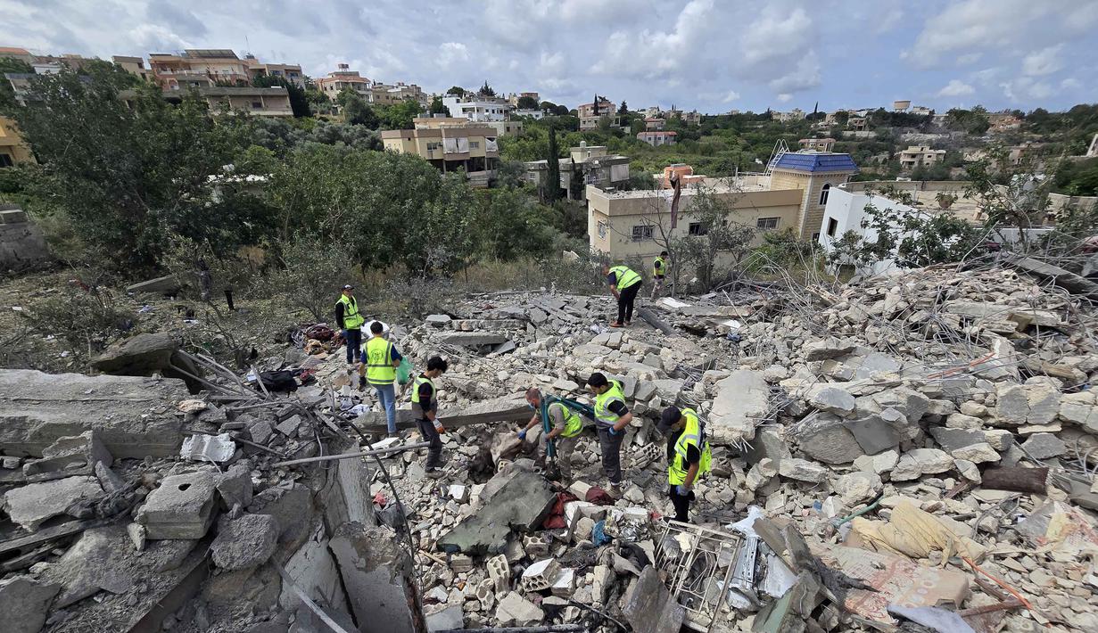 Para pekerja pertahanan sipil Lebanon menyisir reruntuhan, sehari setelah serangan Israel di desa Deir Qanun al-Nahr, Lebanon Selatan, pada Rabu 20 Mei 2026. (KAWNAT HAJU/AFP)