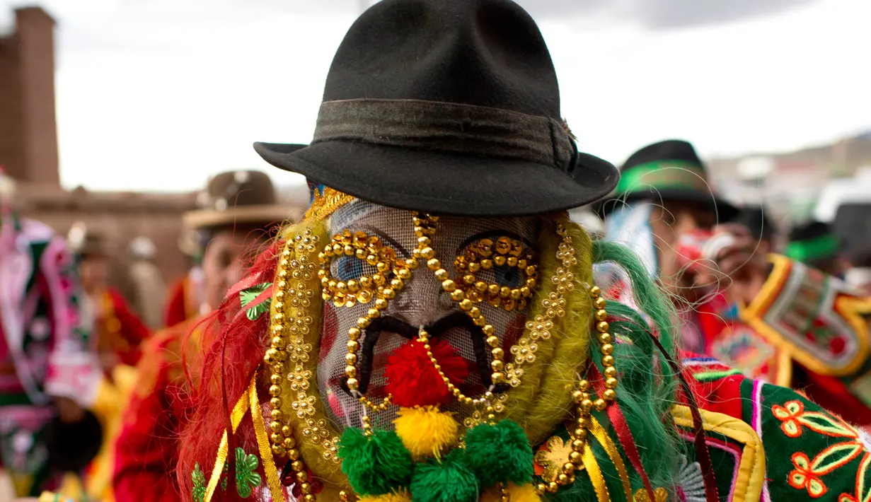 Seorang pria mengenakan kostum lengkap dengan topengnya bersiap mengikuti karnaval Anata Andina (Andean karnaval) di Caquiaviri, Bolivia, Selasa (17/1). Acara tersebut juga dimeriahkan dengan tarian tradisional dan adu banteng. (AP Photo/Juan Karita)