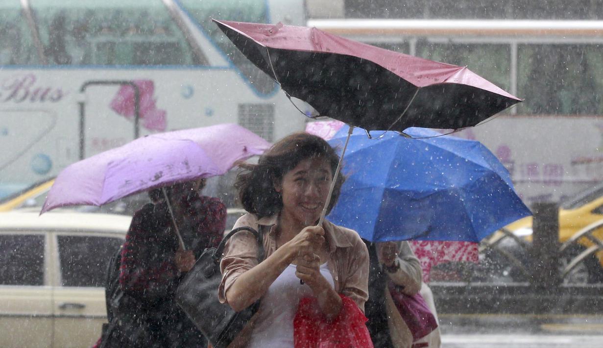 Warga memegang payung sambil berjalan menghindari angin kencang yang disebabkan topan Dujuan di Taipei, Taiwan, Senin (28/9). Ribuan orang diungsikan untuk menghadapi topan raksasa Dujuan yang diprediksikan akan menyerang Taiwan. (REUTERS/Pichi Chuang)