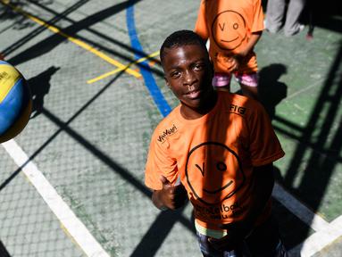 Seorang anak mencoba melambungkan bola voli pada program Volleyball Development Training yang digagas oleh FIVB di Formiga favela, Rio de Janeiro, (2/8/2016). (AFP/Leon Neal)