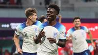 Bukayo Saka berhasil mencetak satu gol dan membantu Timnas Inggris unggul 3-0 atas Iran pada babak pertama&nbsp;laga Grup B Piala Dunia 2022 di Khalifa International Stadium, Senin (21/11/2022) malam WIB. Saka mencatatkan namanya di papan skor pada menit ke-43. (AFP/Adrian Dennis)