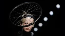 Model mengenakan busana rancangan Moschino dengan hiasan kepala berbentuk roda sepeda dalam Milan Fashion Week Autumn/Winter 2017 di Milan, Italia, (23/2). (AFP Photo / Marco Bertorello)