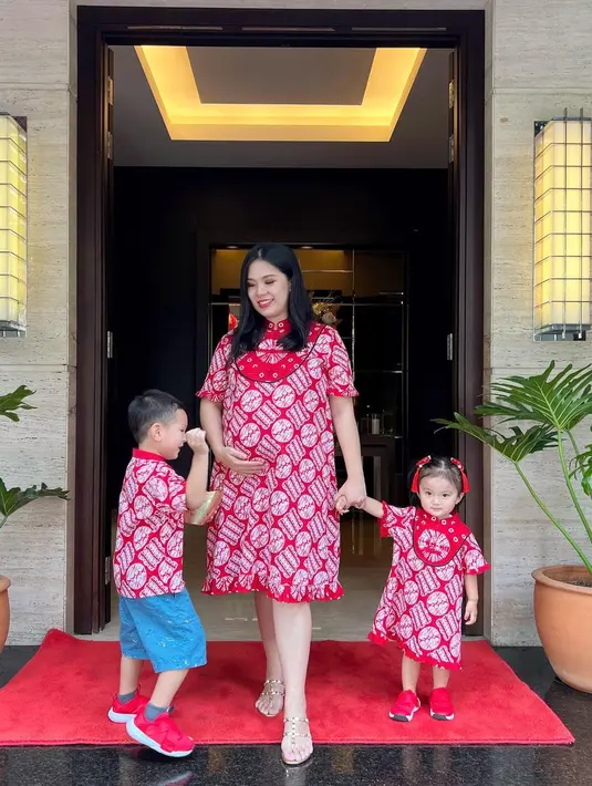 <p>Gaya maternity matching bareng kedua anaknya dengan dress batik simple nuansa merah. (Foto: Instagram @devinahermawan)</p>