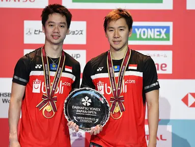 Ganda putra Kevin Sanjaya/Marcus Fernaldi Gideon berpose dengan trofi usai bertanding melawan  Hendra Setiawan / Mohammad Ahsan pada babak fina Jepang Terbuka 2019 di Tokyo (28/7/2019). Kevin / Marcus menang  21-19 dan 23-21.  (AFP Photo/Charly Triballeau)