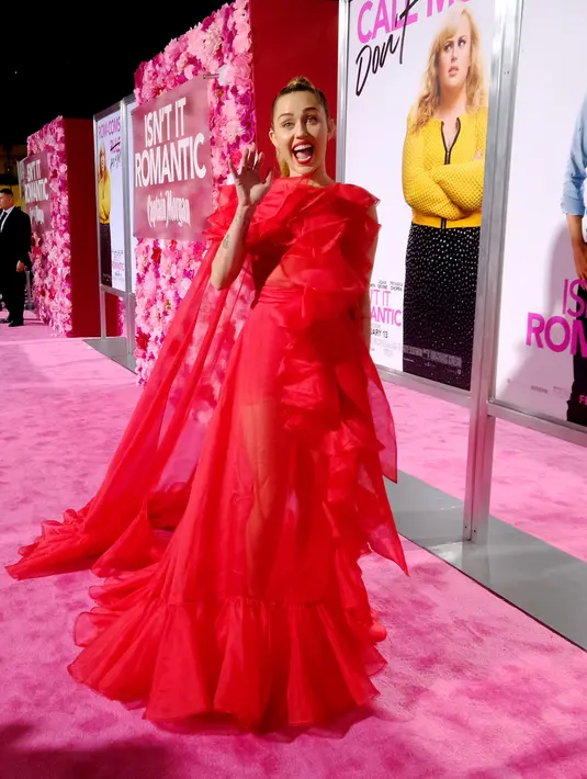 Penyanyi Miley Cyrus menyapa awak media saat tiba menghadiri pemutaran perdana film "Isn't It Romantic" di Los Angeles (11/2). Miley Cyrus tampil memesona dengan gaun berwarna merah Maison Valentino. (AFP Photo/Alberto E. Rodriguez)