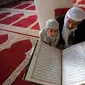 Pria Muslim mendengarkan ketika seorang anak membaca Al-qur'an pada hari pertama bulan suci Ramadhan di Masjid Al-Kabir di kota tua Sanaa, ibu kota Yaman, 2 April 2022. Pada bulan Ramadhan umat muslim memanfaatkan waktu untuk memperbanyak ibadah dengan membaca Al Quran. (MOHAMMED HUWAIS/AFP)