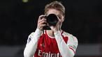 Pemain Arsenal, Martin Odegaard merayakan kemenangan dengan menjadi seorang fotografer setelah laga lanjutan Liga Inggris 2023/2024 melawan Liverpool di Emirates Stadium, London, Inggris, Minggu (05/02/2024) WIB. (AFP/Ian Kington)