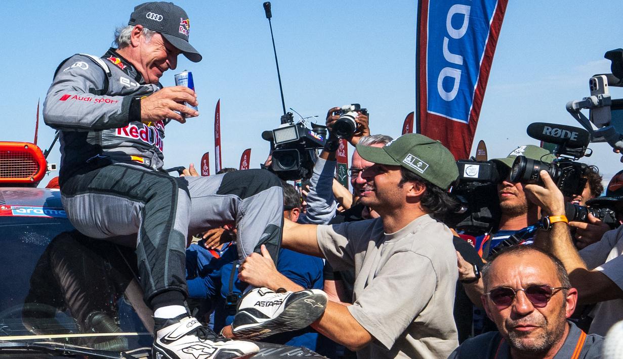 Pembalap Team Audi Sport, Carlos Sainz (kiri) dipanggil oleh sang anak, yang juga seorang pembalap Formula 1, Carlos Sainz Jr saat memenangkan Reli Dakar 2024 setelah menyelesaikan etape terakhir di Yanbu, Arab Saudi, Jumat, 19 Januari 2024 waktu setempat. (AFP/Patrick Hertzog)