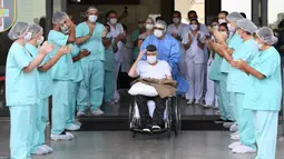 Veteran Perang Dunia II asal Brasil, Ermando Armelino Piveta meninggalkan Rumah Sakit Angkatan Bersenjata setelah pulih dari covid-19 di Brasilia, Selasa (14/4/2020). Mengenakan topi militer, kakek berusia 99 tahun tersebut mengangkat tangannya saat meninggalkan rumah sakit. (EVARISTO SA/AFP)