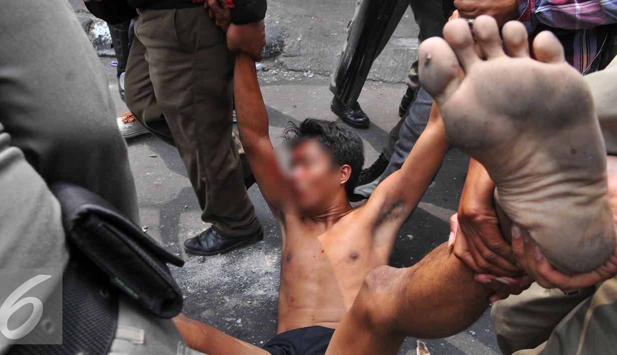 Seorang warga diamankan Petugas saat penggusuran Kampung Pulo, Jakarta, Kamis (20/8/2015). Penggusuran pemukiman Kampung Pulo dilakukan oleh 2.200 personel gabungan untuk normalisasi Sungai Ciliwung. (Liputan6.com/Herman Zakharia)