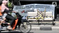 Pengendara melintasi bangku trotoar yang disegel garis pembatas dan ditutupi bambu di kawasan Rawamangun, Jakarta, Minggu (3/5/2020). Bangku trotoar di sepanjang jalan Rawamangun disegel untuk mencegah kerumunan warga sebagai upaya memutus rantai penyebaran COVID-19. (merdeka.com/Iqbal S. Nugroho)