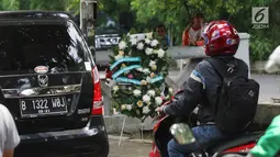Kendaraan melintas dekat karangan bunga yang bersandar pada tiang lampu di Jalan Permata Berlian, Jakarta, Sabtu (18/11). Tiang itu mendadak menajdi perhatian banyak orang karena ditabrak mobil yang ditumpangi Setya Novanto. (Liputan6.com/Angga Yuniar)