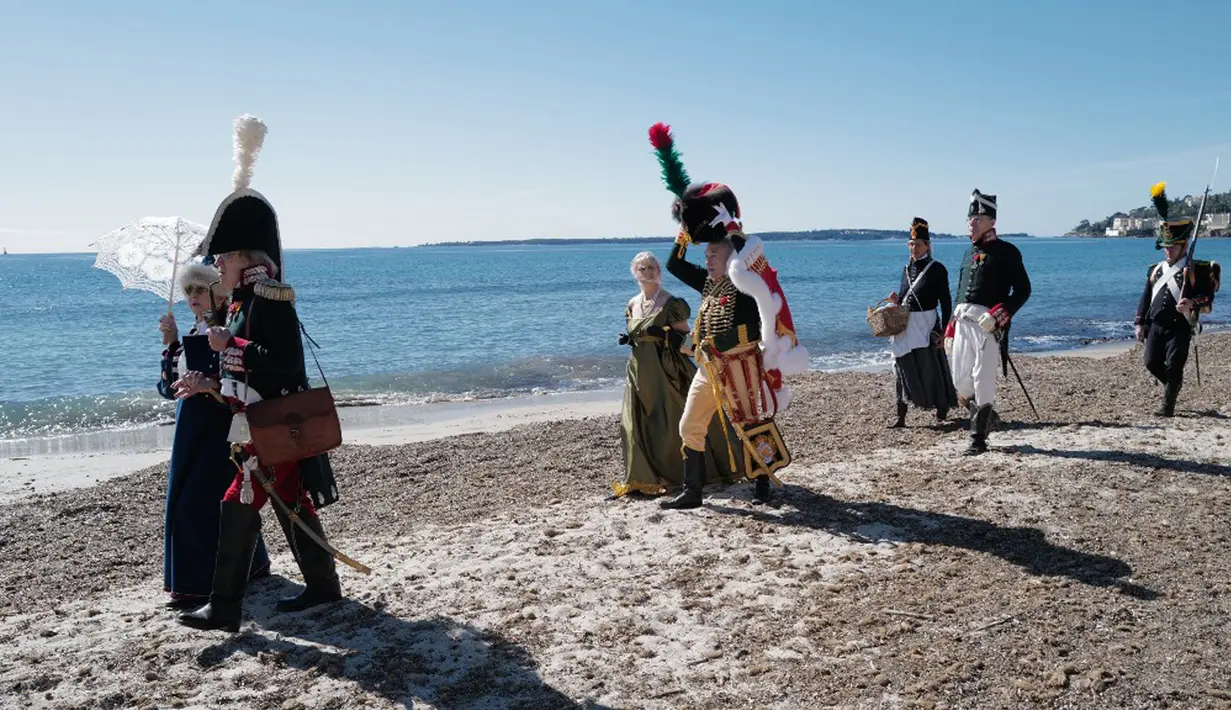 Orang-orang yang mengenakan kostum era Napoleon Bonaparte berjalan di pantai dalam rangka peringatan 200 tahun kematian Napoleon Bonaparte di Saint-Helene, Golfe-Juan, Prancis, 16 Maret 2021. Sebagai Napoleon I, ia adalah Kaisar Prancis dari tahun 1804-1814, dan kembali pada 1815. (Valery HACHE/AFP)