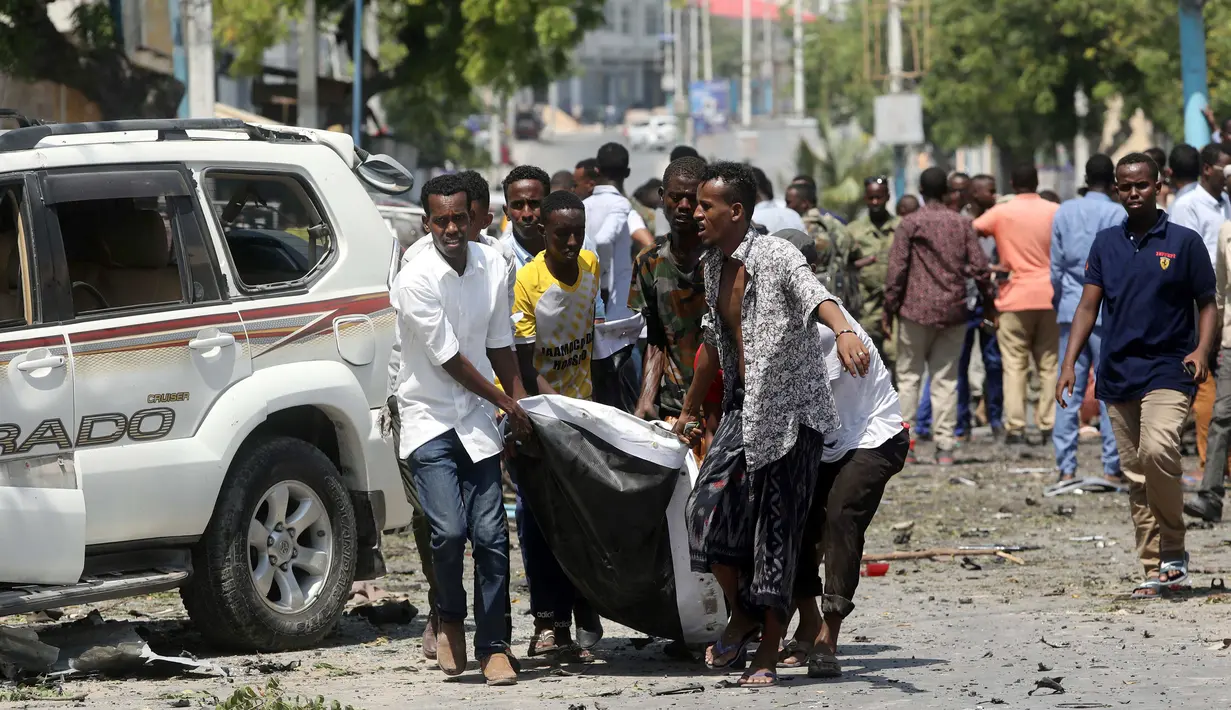 Sejumlah warga sipil membawa mayat seorang pria yang tewas di lokasi ledakan dekat sebuah hotel di Mogadishu, Somalia (28/3). (Reuters/Feisal Omar)