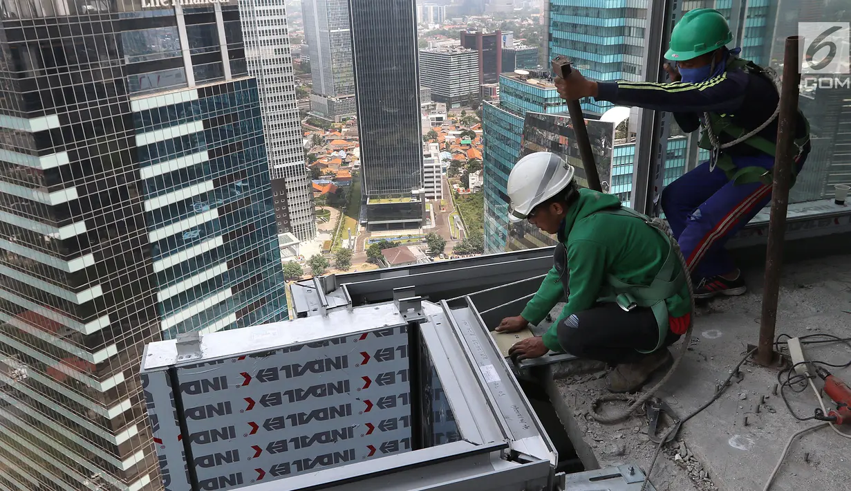 Pekerja Nusa Konstruksi Enjiniring memasang kaca gedung World Capital Tower, di Mega Kuningan, Jakarta, Rabu (13/9). Deretan gedung perkantoran masih menghiasi di ibukota Jakarta. (Liputan6.com/Fery Pradolo)