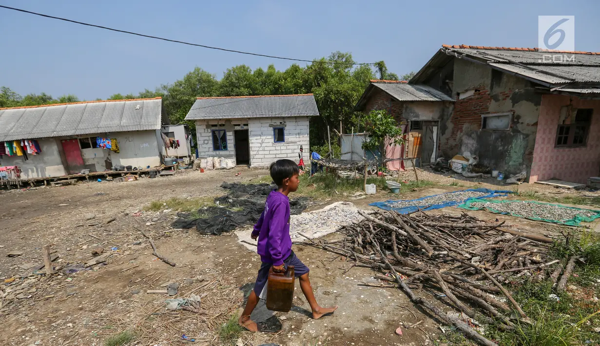 Seorang anak melintas di depan rumah warga yang memilih bertahan di Desa Pantai Mekar, Kecamatan Muara Gembong, Bekasi, Kamis (20/6/2019). Puluhan rumah warga di Kampung Muarajaya RT01/RW01 Desa Pantai Mekar hilang tersapu air saat terjadi abrasi selama 10 tahun. (Liputan6.com/Fery Pradolo)