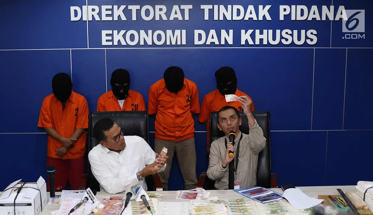 Wakil Direktur Tipideksus Bareskrim Polri Kombes Pol Daniel Tahi Monang Silitonga (kiri) menunjukkan barang bukti beserta tersangka jaringan uang palsu di Jakarta, Rabu (18/4). (Liputan6.com/Immanuel Antonius)