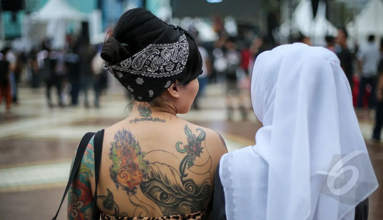 Sejumlah wajah nyentrik bermunculan di acara Indonesia Greaser Party 2015, Plaza Barat Senayan, Jakarta, Minggu (12/4/2015). Tampak seorang wanita memperlihatkan punggungnya yang bertattoo. (Liputan6.com/Faizal Fanani)