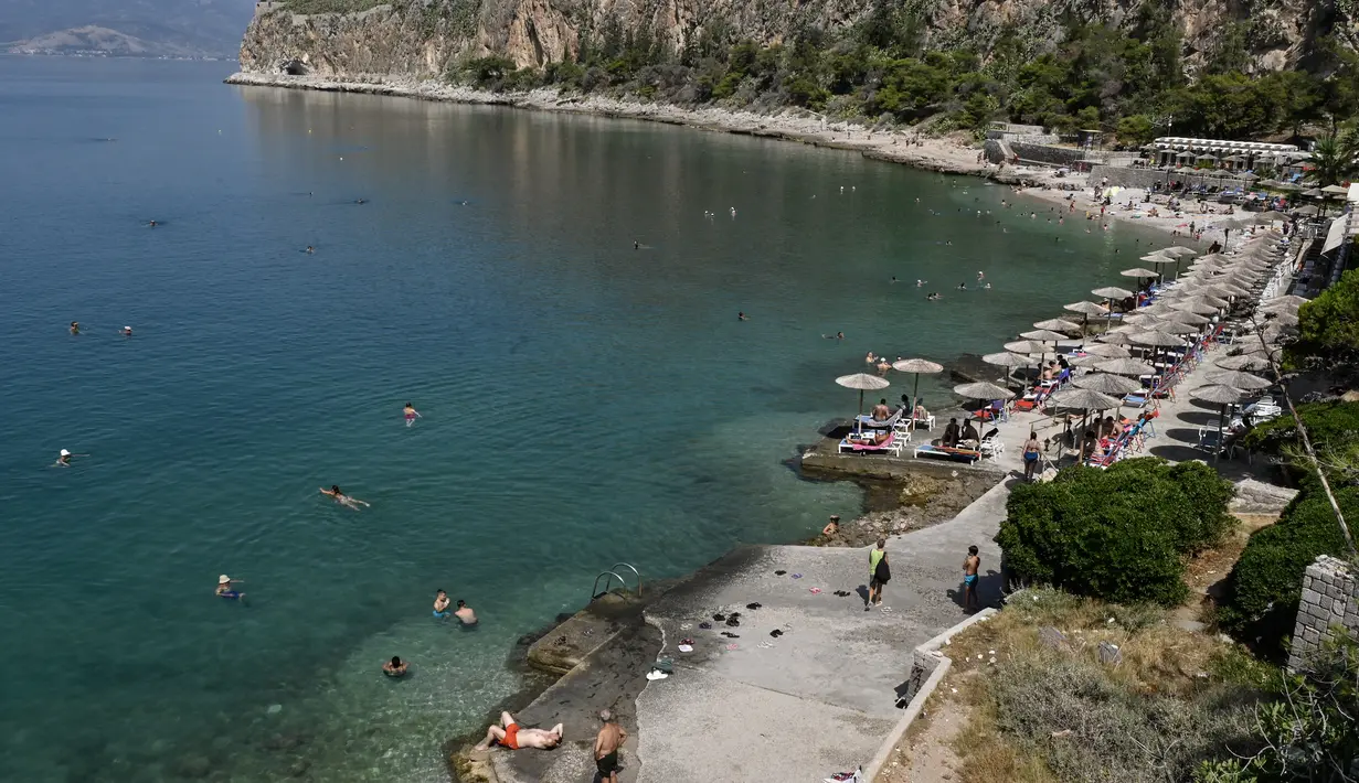 Penduduk setempat dan turis mendinginkan diri di sebuah pantai di kota wisata Nafplion, sekitar 200 km barat daya Athena selama cuaca panas di Yunani, pada 14 Juli 2023. (AFP/Louisa Gouliamaki)