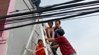 Seorang pria tersetrum saat hendak membantu memperbaiki atap tetangganya di Kosambi, Kabupaten Tangerang, Jumat (22/7/2022) (Liputan6.com/Pramita Tristiawati)