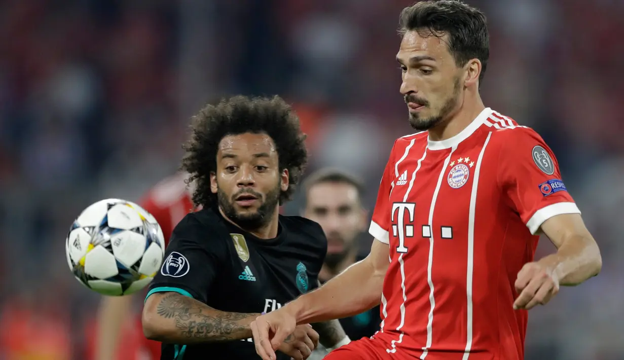 Pemain Real Madrid, Marcelo berebut bola dengan pemain Bayern Munchen, Mats Hummels pada leg pertama semifinal Liga Champions di Allianz Arena, Rabu (25/4). Real Madrid meraih kemenangan 2-1 saat bertandang ke markas Bayern Munchen. (AP/Matthias Schrader)