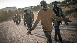 Para migran berjalan setelah melintasi pagar yang memisahkan kantong Spanyol Melilla dari Maroko, di Melilla, Spanyol (3/3/2022). Pemerintah Spanyol di Melilla mengatakan 380 dari 1.200 migran berhasil mengatasi penghalang ganda 6 meter (20 kaki) yang mengelilingi kota. (AP Photo/Javier Bernardo)