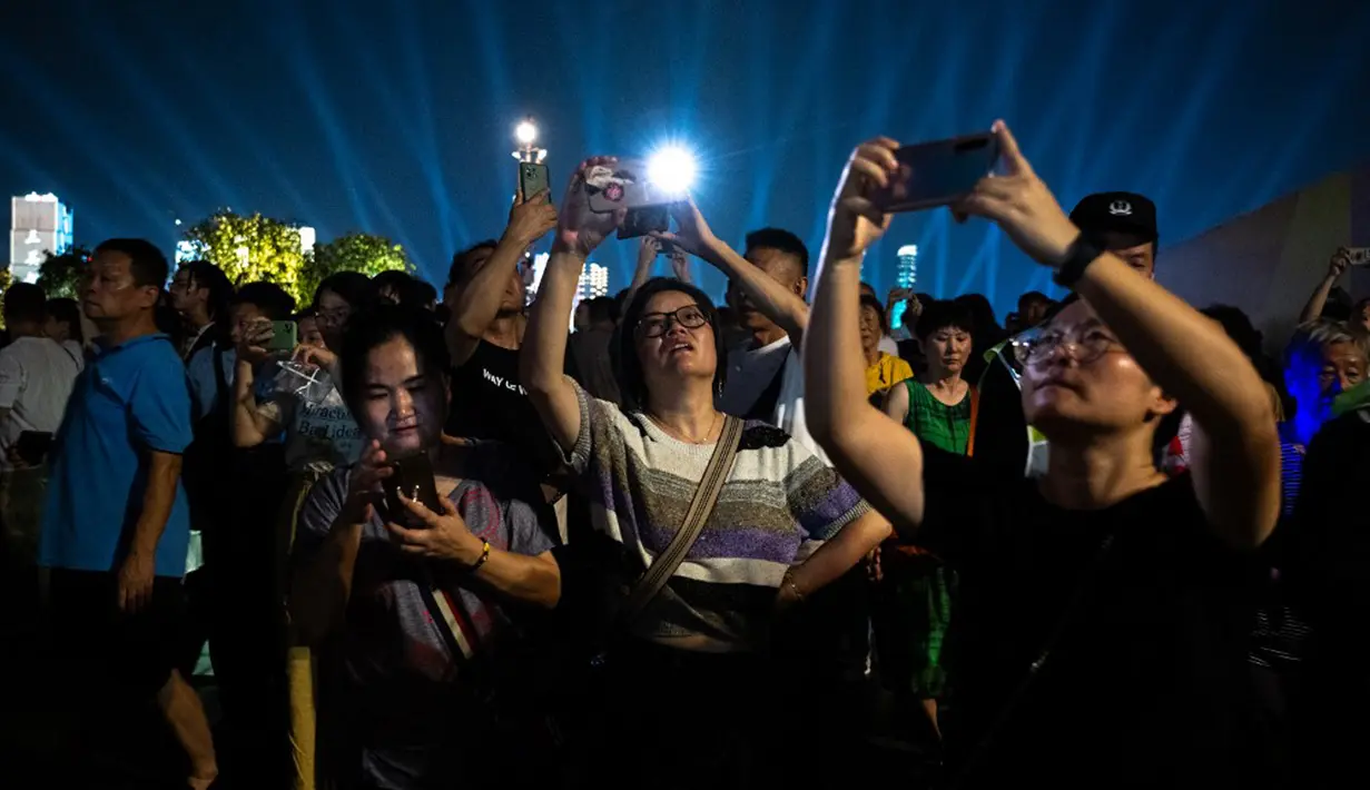 Warga yang antusias menyaksikan pertunjukan cahaya di Hangzhou Olympic Sports Centre Stadium tampak mengabadikan momen indah tersebut dengan ponsel mereka. (Philip FONG/AFP)