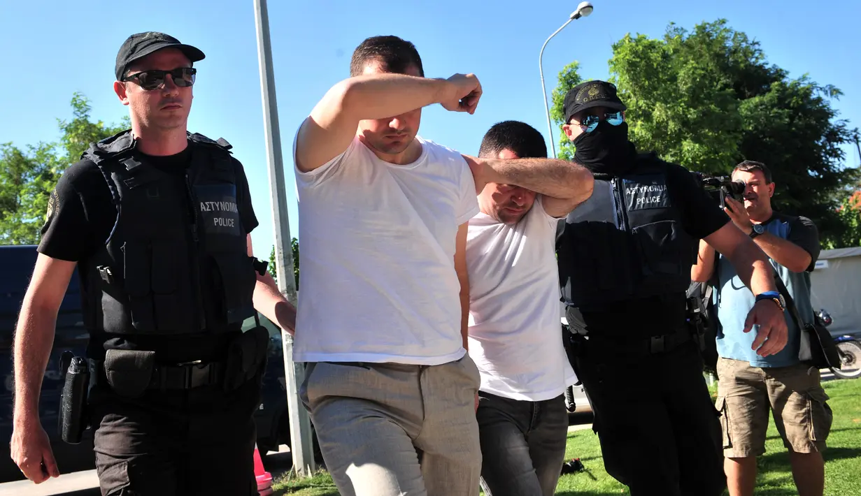 Dua dari 8 perwira militer pendukung kudeta di Turki dikawal polisi Yunani di kota Alexandroupoli, Minggu (17/7). 8 pria yang terbang dengan helikopter militer Turki itu ditahan petugas keamanan Yunani karena masuk secara ilegal. (Sakis MITROLIDIS/AFP)