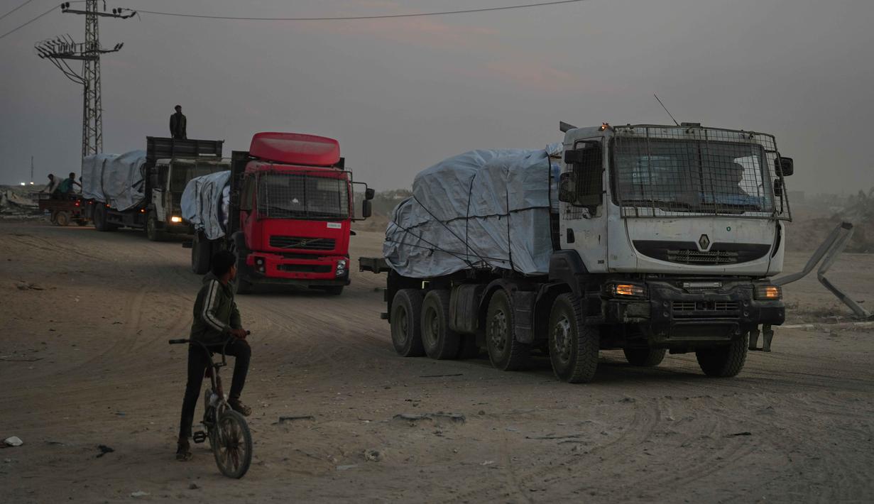 Kantor Perserikatan Bangsa Bangsa (PBB) untuk Koordinasi Urusan Kemanusiaan (OCHA) secara terang-terangan menyatakan bahwa jalur penyaluran bantuan masih sangat terbatas. Tampak dalam foto, truk-truk yang mengangkut bantuan dari Program Pangan Dunia (WFP) melintasi Deir al-Balah, bagian tengah Jalur Gaza, pada Sabtu, 8 November 2025. (AP Photo/Abdel Kareem Hana)