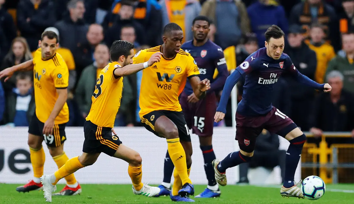 Megaintang Arsenal, Mesut Ozil menggiring bola dibayangi oleh pemain Wolverhampton Wanderers pada laga lanjutan Liga Inggris 2018-2019 di Stadion Molineux, Rabu (24/4). Arsenal harus tumbang dengan skor 1-3 kala bertandang ke markas Wolverhampton Wanderers. (REUTERS/Eddie Keogh)