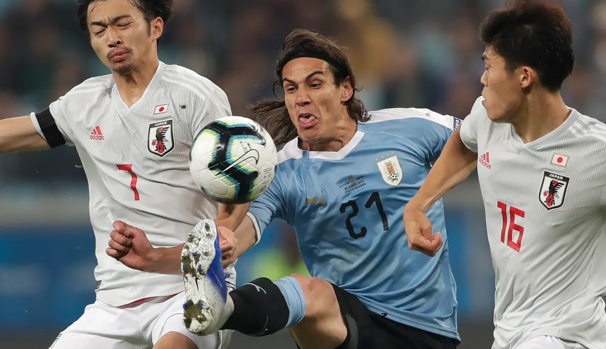 Striker Uruguay, Edinson Cavani berusaha melewati dua pemain Jepang, Takehiro Tomiyasu dan Gaku Shibasaki selama pertandingan grup C Copa America 2019 di Arena Gremio di Porto Alegre, Brasil (20/6/2019). Jepang bermain imbang 2-2 atas Uruguay. (AP Photo/Silvia Izquierdo)