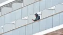 Penumpang bermain ponsel saat dikarantina di balkon di atas kapal pesiar Diamond Princess di Daikoku Pier Cruise Terminal di Yokohama (7/2/2020). Kementerian Kesehatan Jepang mengonfirmasi 41 penumpang kapal pesiar itu positif terinfeksi virus Corona. (AFP/Jiji Press)