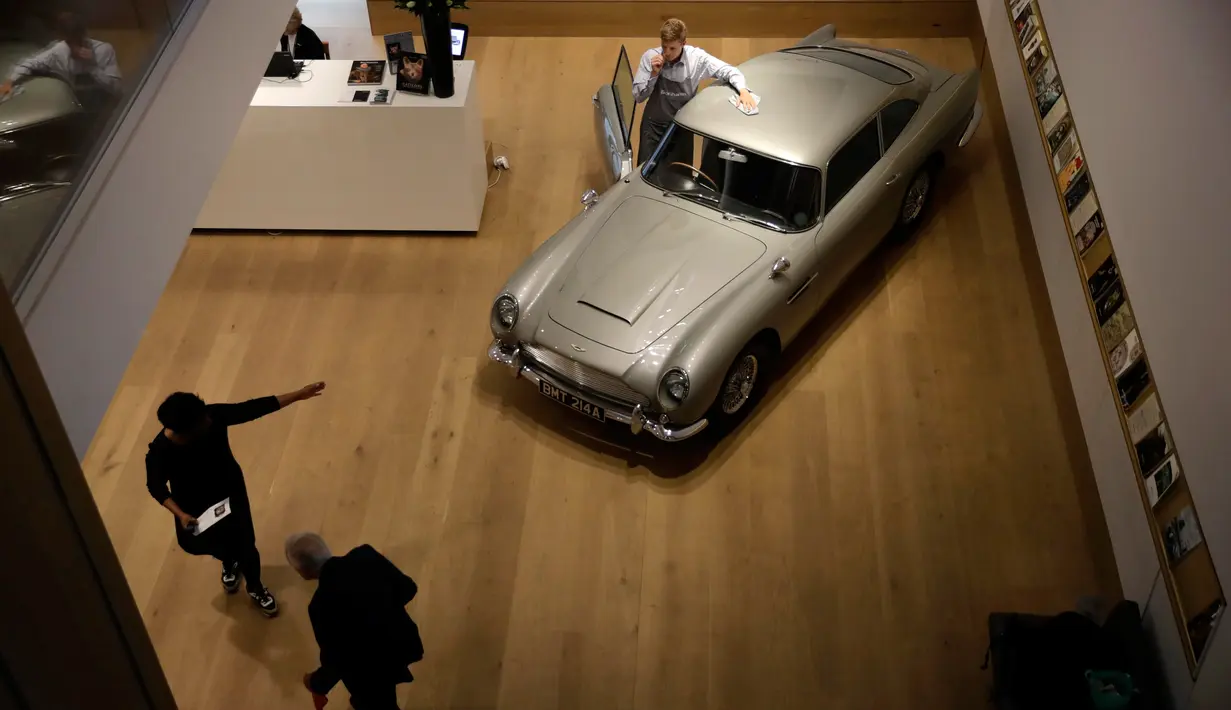 Seorang staf berpose dengan Aston Martin DB5 yang digunakan dalam film James Bond GoldenEye tahun 1995 rumah lelang Bonham, London, Selasa (19/6). Mobil itu diperkirakan harganya mencapai 1,6 juta pound sterling atau sekitar Rp30 miliar. (AP/Matt Dunham)
